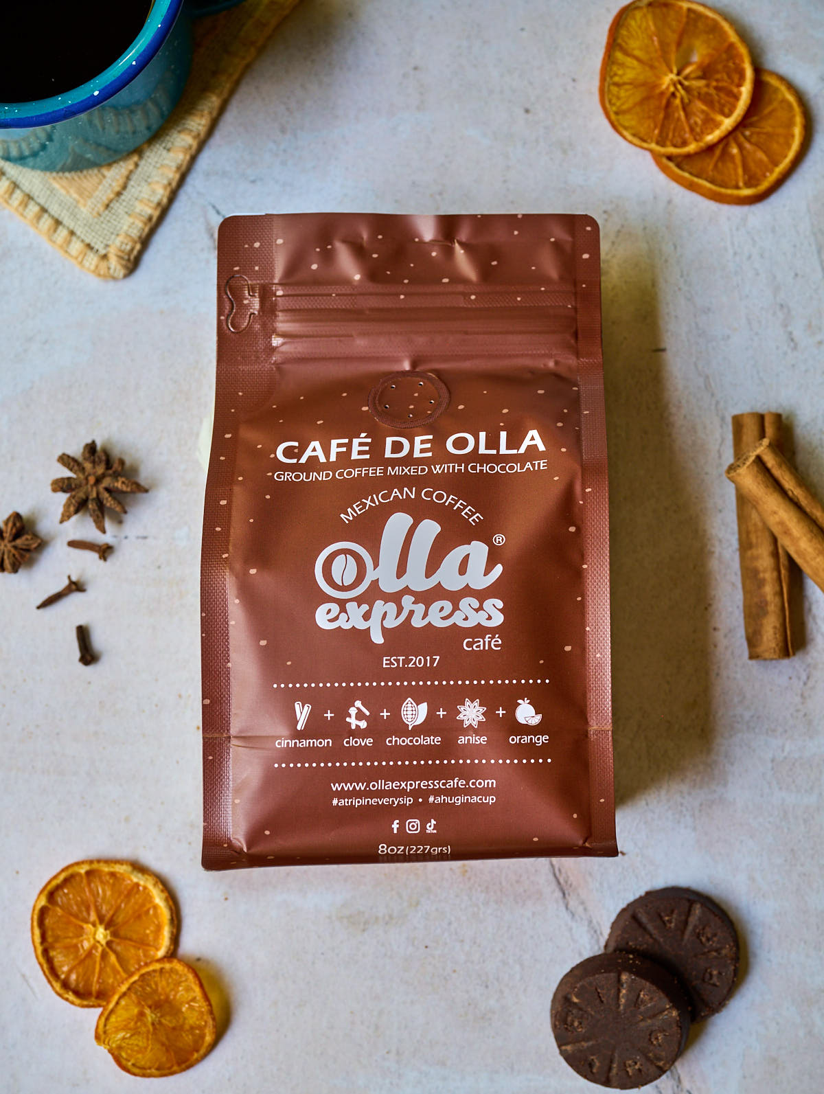 Café de Olla coffee package with dried oranges and cinnamon sticks and mexican chocolate on a light surface